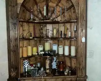 Corner cabinet filled with candlesticks/candles/etc.