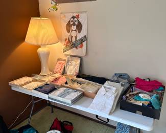 Here is a table filled with NEW Old Stock clothing. All in their regional packaging, or original boxes, and many with the receipts! Love the two SWATCH bags onto floor under the table!