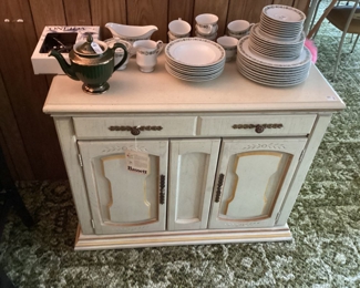 Bassett Dining Room Cabinet. Topped with a Dish Set by Sanyo Tiveil. Vintage Hall Teapot and a set of Oneida Stainless Silverware