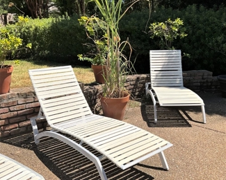 Three pool-side white lounge chairs