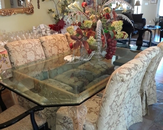 Large glass top dining table with carved wood base that seats 8.