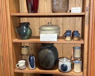 Den:  Beautiful pottery on the top shelf is by the artist  "Mueller;" the pottery on the lower three shelves is by the artist  Brian VanNostrand, a West Virginia potter.  VanNostrand uses a variety of clays that he finds on his farm and near areas.   He uses time-consuming processes, so his production is limited.  You won't find much of his work available in other places. 