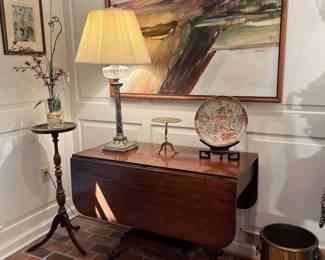 Dining Room:  A large piece of original art (48" x 38") by Missouri artist Chiara Moerschel hangs above an antique drop leaf table (see next photo of base); a silver-plate/crystal lamp; a brass squirrel trivet; an Asian-theme plate on stand; and a heavy brass vessel (great for a plant or kindling wood).  To the left is an etching and a faux plant on a fern stand.