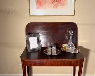 Family Room:  An antique game table displays a WATERORD crystal photo frame, small glasses, and a decanter.  The abstract art above is by "Barbara Glenberg."