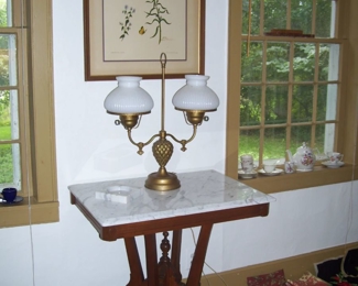 VICTOORIAN MARBLE TOP PARLOR TABLE AND VICTORIAN STYLE DOUBLE ARM BRASS LAMP IN PARLOR - NEEDLEPOINT WALL DECOR