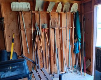 Assorted long handled metal shovels; hedge trimmer; branch trimmer;  12-tine bedding/hay pitch fork; tamper bar;  long handle axe; Sledge hammer; splitting wedge; snow shovels; 