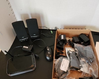 Netgear router, small desk speakers, mouse and assorted adapters