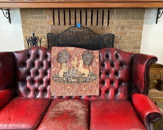 Red leather couch with tapesery