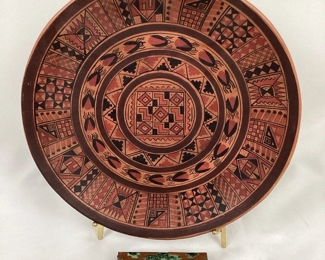 JIFI104 Peruvian Plate Colombian Cigarette Box: This is a beautifully painted Peruvian clay plate and a pre-Columbian styled enameled copper box. The plate features several&nbsp;painted&nbsp;Mesoamerican depictions of beattles, as well as various symmetrical Peruvian patterns. The enameled copper box is most likely a cigarette holder, and features a central image of a pre-Columbian figure or god on it's lid.
