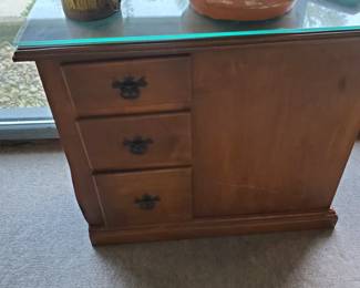 This piece is lovely.  Three doors on the front with side drawer on the right side.  Full glass cover the top.  Will slide between a sofa and chair easily.