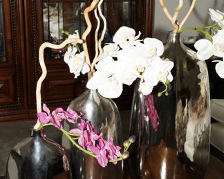Z Gallerie chrome vases with faux orchids and decorative sticks. There are three sizes to choose from when buying these pieces.