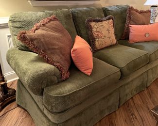 green fabric sofa, throw pillows, lamps, clocks, floor lamp, ceramic table lamp