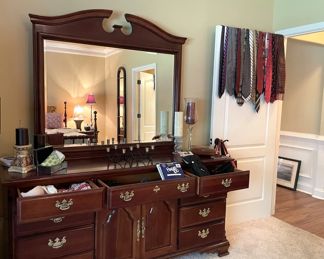 large bureau, chest of drawers with mirror, neckties, decorative candle holders, candles, wall art, full-length mirror