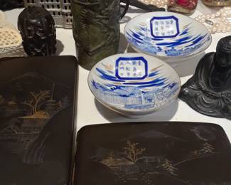 Cigarette cases, ceremonial sake bowls, unusual bank in background, pale pink cloisonne vase in far background.