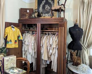 Selection of antique christening gowns and children's clothing.  Rosewood salesman's sample chair, Victorian feather wreath.