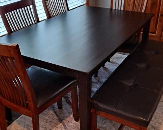 Stained Black Wood Dining Table with Four Wood Chairs and a Leather Covered Bench; Decorative Area Rug