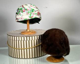 (2PC) WOMEN’S HEAD WRAP AND FUR HAT WITH STANDS | Includes round fur hat from Green Room Millinery Bloomingdale’s and color hair wrap by Cindy, each with wooden stand in striped golden hat box. -  h. 7 x dia. 14 in