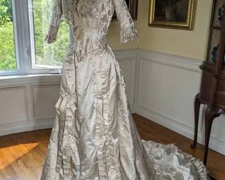 21)  ca 1881  Beaded Brocade Bridal Gown with lace.  Gown is labeled Field Leiter &  Co, Chicago. Gown is one piece made to look like 2 pieces.  Satin front with bows.  Gown has its own bustle underneath.  Each underarm has a slight stain but no damage.  There is one small tear in the train. Large train.  Very small size.  According to paperwork when gown was bought, gown is attributed to Alice Sheldon Mathews, Married to Albert Blake Dick of the AB Dick Company on January 25, 1881. Information will be included with gown.  Gorgeous gown!!  Near Mint Condition.   Measures: Shoulder to Shoulder  - 11",  Bust 32"-  Waist - 22",  Length 56",  Length with train - 96"    $3400.00  Sale:  2550.00
