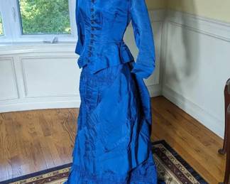 25)  ca 1880's Blue Bustle Gown.  Bodice has minor underarm discoloration and the hooks for the waist band to attach the bustle are missing.  Otherwise, in excellent condition.  Measures:  Bodice: shoulder to shoulder 14", Bust - 26",  Waist - 22",  Length - 21".  Skirt:  Waist - 24",  Length - 40" Total length - 61".    $ 725.00  Sale:  $543.00
