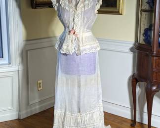 47.)  Ca 1870's 3 piece gown, lace and embroidered Dress with pink ribbons.  Mixed laces.  Trained.  Accommodation for bustle made of lace and pink bows.  Inner piece under top.  I'm not quite sure what this is - possible corset cover (?).  Some age discoloration I believe will come out but won't guarantee.  1 button missing on waist band of skirt and all buttons on corset cover missing.  Nice ruching on flounce of skirt.   Measures:  Top:  shoulder to shoulder 16", Bust: 28", Waist 26", Length: 21".  Skirt - Waist: 25", Length 42", Length with train 55".   $495.00