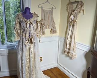 3.)  3 Piece  Ensemble. (second piece hanging behind first piece on the wall. )  Linen with satin bows.  Mixed Laces.  Trained.  Ensemble has a lot of age discoloration.  I believe it will clean out but cannot guarantee.   1 large hole in back of dressing gown.  Measures:  Dressing gown:  shoulder to shoulder - 12", Bust - 34", Waist - 34" Length 66", length with train - 72".  Inner piece:  Bust - 32", Waist - 34", Length 43".        $495.00