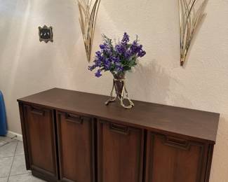 Wilkommen, Bienvenue, Welcome...Entryway MCM console / buffet, Brass Flower Wall Hangings, Bombay Co. Floating Glass Vase in Brass Stand.