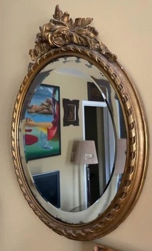 Oval antique giltwood - framed beveled mirror.