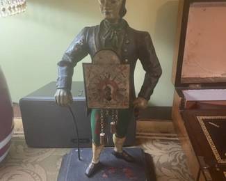 Vintage figural cast iron key-wind clock statue with key, colonial period style.