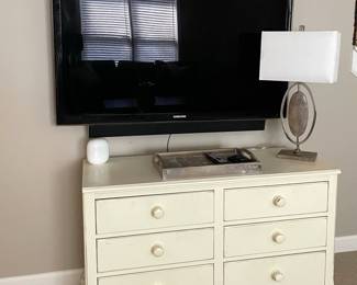 ivory wood chest of drawers, television, table lamp, decorative tray.