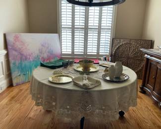 circular dining table, fine linens, serving dishes, sideboard, wooden wall art, large abstract wall aret