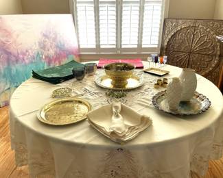 circular dining table, fine linens, serving dishes, sideboard, wooden wall art, large abstract wall aret