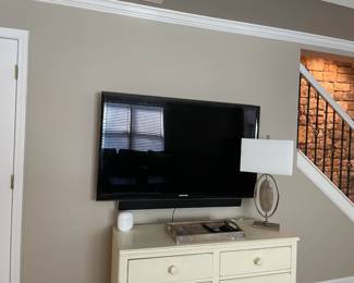 ivory wood chest of drawers, television, table lamp, decorative tray.