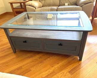 Oak coffee table refinished in gray stain. Glass top and two deep drawers.  