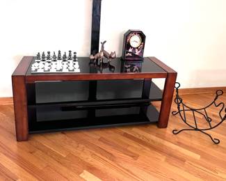 Marble onyx chess set on TV stand with three smoke glass shelves. Fireplace log stand, brass cat figurines. 