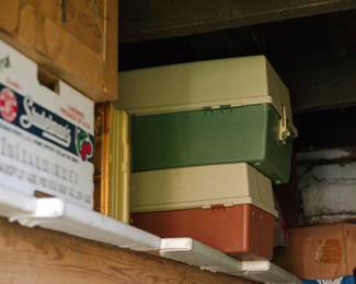 Two vintage tackle boxes: green with a cream lid and red with a cream lid