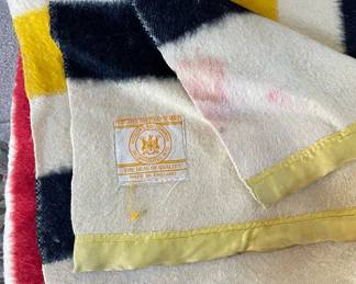 Folded detail of Hudson's Bay Point blanket, cream with black, yellow, red, and green stripes