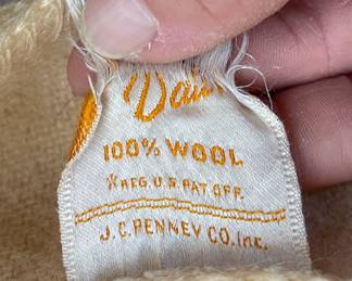 Tag detail of Hudson's Bay Point blanket, cream with black, yellow, red, and green stripes, 100% wool