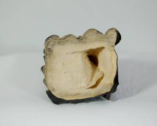 Bottom of sculpture of a nun wearing a habit, kneeling and praying with a crucifix in her lap