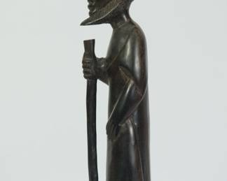 Side view of African wood sculpture of a bearded man holding a staff