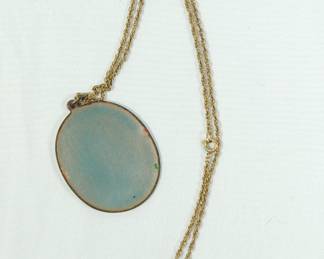 Backside of cool enamel pendant with a copper horse head on white background with small red flowers. Pendant is on a brass rope chain. Enameled back is light blue.