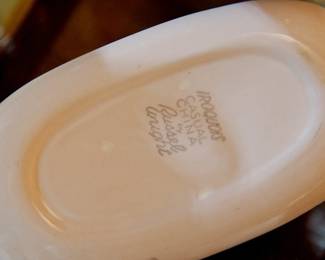 Bottom detail of 1950s Russel Wright Iroquois Casual Pink Sherbet set of dishes including 1 small serving plate, 8 teacups with saucers, 4 bowls, and 8 dinner plates