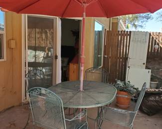 Vintage wrought iron patio dining set with red umbrella. 42x54