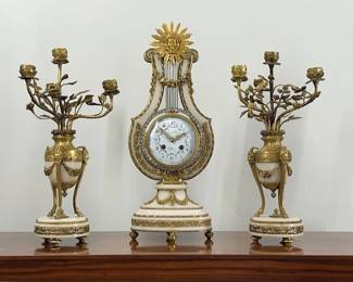 Fine & Rare Louis XVI Style Gilt-Bronze & Marble Lyre Form Clock and Four-Light Candelabra Garniture.   Eight day bell striking movement.  Hand painted enamel dial signed by the Paris merchant.  Gridiron pendulum with ring of paste diamonds encircles the bezel.   Circa 1900.  $4,850
