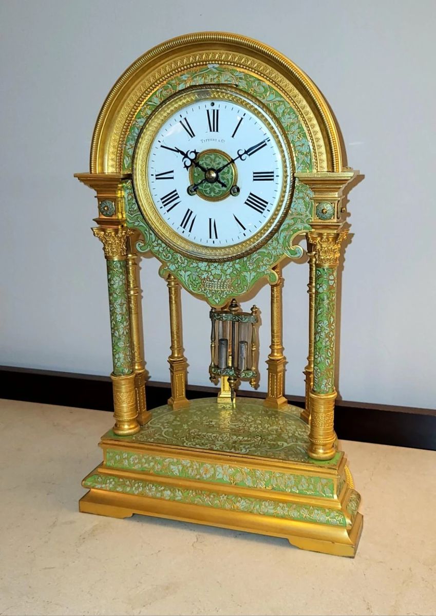 Tiffany & Co. Masterpiece.  A circa 1890 showpiece of style, materials, workmanship, proportions and quality.  In fifty years of appraising, restoring and collecting clocks of merit, I've never encountered anything comparable to this gilt-bronze and champleve stunner.   The 18.5" high x 11.25" wide x 7.5" deep case exhibits elements of classical architecture as well as orientalist decorative motifs in two shades of enamel.  Flawless fired enamel dial.  6.25" diameter bezel hinged from the top.  Eight-day movement striking on a resonate coiled steel gong.   Enamel enhanced two vial pendulum.  Original throughout and very well maintained, with modest gilt wear at the domical top.   Operating order - at buyer's request, the movement can be professionally serviced to ensure years of reliable operation.  $4,850