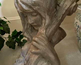 Cast sculpture of woman playing stringed instrument.