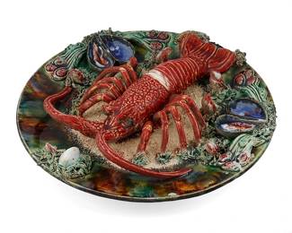 1129
Late 19th/early 20th century; Portugal
A Portuguese Palissy Glazed Ceramic Lobster Platter
Stamped to the verso: Alvaro Jose Caldas / da Rainha / Portugal
The majolica three-dimensional hanging wall platter with realistically rendered ceramic lobster, mussels, and barnacles amongst textured sea vegetation and sand, all glazed in shades of red, green, blue, and brown
2.25" H x 12.5" Dia.
Estimate: $500 - $700