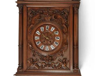 1130
Late 19th century
A Horner-Style Carved Wood Wall Clock
Appears unmarked
The two-train movement clock with enameled metal Roman numeral dial and carved wood front panel depicting dragons and griffins at the corners, housed in a rectangular carved wood case featuring turned columns and a molded drop finial with scrolled acanthus motif
50" H x 24" W x 9.25" D
Estimate: $1,000 - $2,000