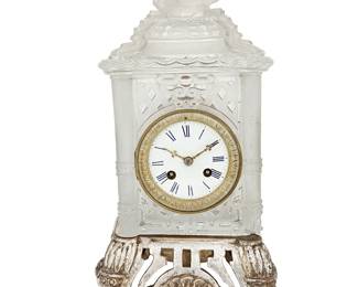 1163
Late 19th century
A French Frosted Glass Chinoiserie Mantel Clock
Marked to movement: Tiffany & Co. / 1067
Possibly Baccarat, with a Tiffany & Co. two-train movement, black Roman numerals on the enameled metal dial set in a brass tongue and dart frame, housed in a frosted glass architectural pagoda carcass surmounted by a high relief Fu lion finial, set on a later added white gold-leafed wood base with an openwork apron and scrolled feet
With base: 16" H x 8.75" W x 8" D
Estimate: $1,500 - $2,500