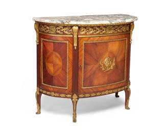 1231
20th century
A Transitional Louis XV/XVI-Style Marquetry Demilune Commode
The wood cabinet featuring marquetry veneer and mounted gilt-bronze trim and accents in egg-and-dart and scrolled laurel wreath patterns with a higher relief mask centering the latch-locked front cabinet door, revealing and open cavity, all surmounted by a beveled white and brown marble top and supported on four curvilinear legs with gilt-bronze paw feet
40.125" H x 46.5" W x 22.25" D
Estimate: $800 - $1,200