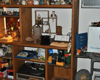 Large oak open shelving unit, antique wooden crate, decorative wooden trees, child's tall stool, MCM decor, collection of studio pottery, wooden animal articulated figures, stereo, Canon rebel XT w/Canon lenses, Konica, Minolta, film, steins, WWII framed yard-long Army photo, United Delco cabinet, metal Lexco office typewriter table dropleaf w/wheels.